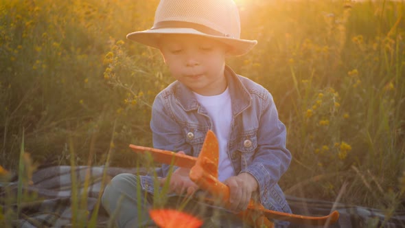 Happy Little Boy Playing with a Toy Airplane in Nature During Sunset. Dreams of Traveling Concept.