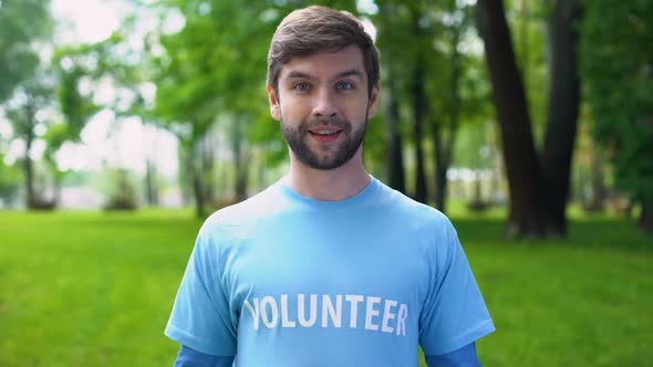 Happy Male Activist Pointing at Volunteer Word on Blue T-Shirt