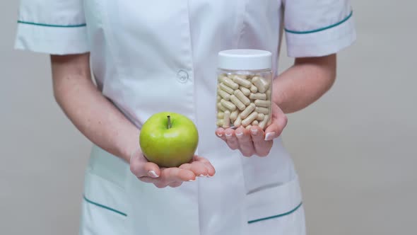 Nutritionist Doctor Healthy Lifestyle Concept - Holding Organic Green Apple and Jar of Vitamin Pills