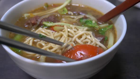 Close up of Stirring steaming beef noodle soup