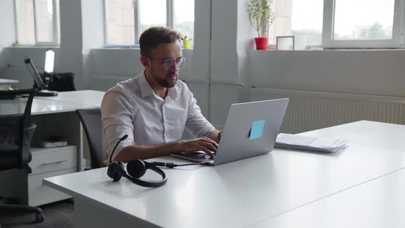 Back View of a Man That Sits at the Grey Laptop