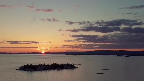 High View of Rocky Pine Tree Island in Blue Lake at Sunset, Drone Aerial Wide Dolly Out. Colorful Cl