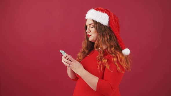 Shocked Oversize Woman in Santa Christmas Hat Using Mobile Phone Receiving Message and Enjoying