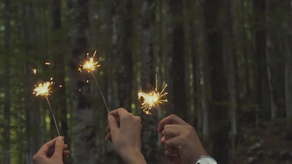 Crop couple with burning sparkle in woods