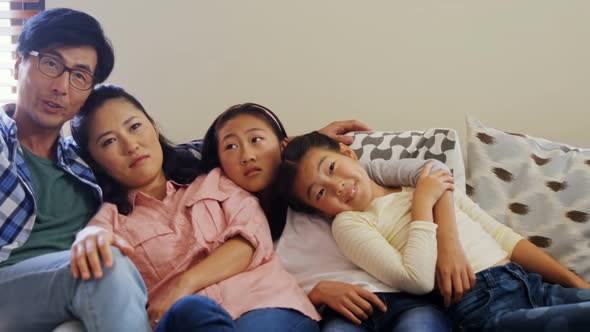 Smiling family relaxing on sofa in living room 4k