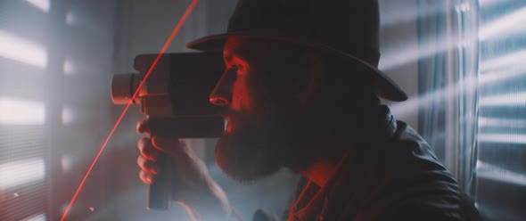 Side view of man holding vintage camera through laser light