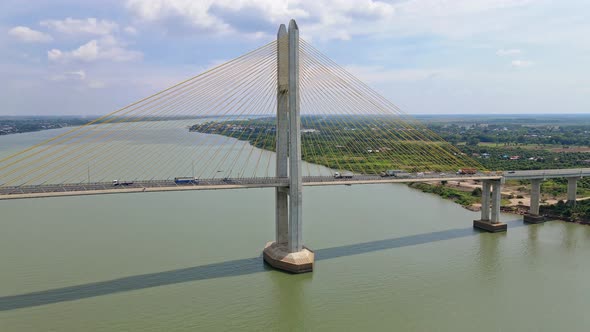 Aerial flight towards famous Tsubasa bridge with driving cars and trucks over Mekong River and rural