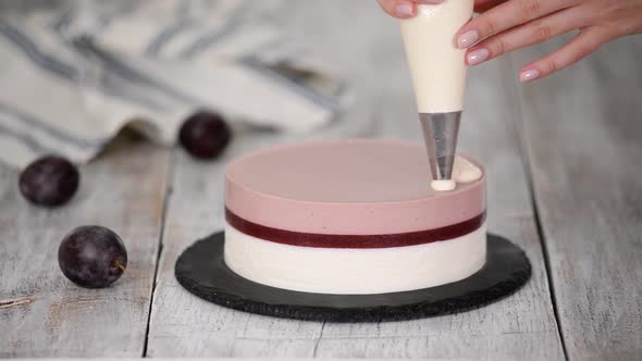 Pastry chef decorated a delicious plum mousse cake with whipped cream.