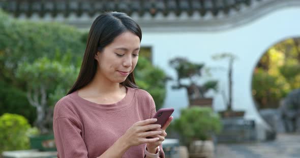 Woman use of mobile phone inside chinese garden