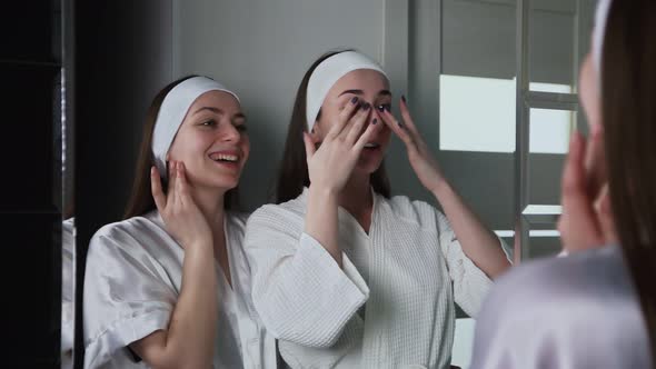 Two Young Woman Looks at the Mirror After Beauty Cosmetology Therapy