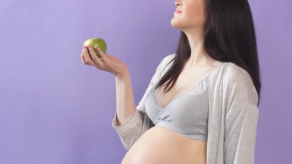 Pregnant Slim Woman with Big Belly Holding Apple Isolated Over Blue Wall