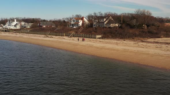 a low drone view over the calm waters by a beach in Orient Point, NY, on a day with blue skies. The