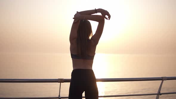 Backside View of a Slim Long Haired Girl Looking to the Sunrise Near the Water