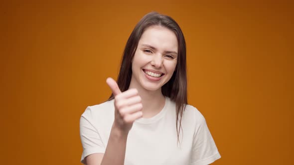 Young Woman Laughing of a Joke and Showing Thumbs Up Yellow Background