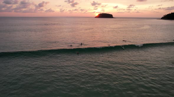 Surfers Catch Waves at Sunset