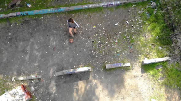 Aerial view of girl kicking a soccer ball against wall, practicing alone before the game