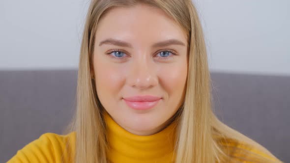 Video portrait of attractive young blonde woman with blue eyes posing with cheerful smile in 4k