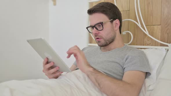 Upset Beard Young Man Get Shocked on Tablet in Bed