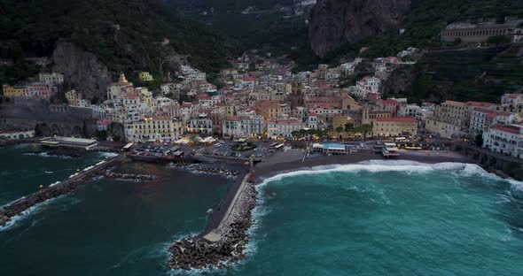 Dramatic setting of town below steep cliffs on coastline, Amalfi; aerial