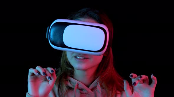 Young Woman in VR Glasses Closeup. A Woman Immersed in Virtual Reality Makes Movements with Her