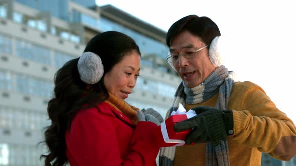 Couple in warm clothing holding gift