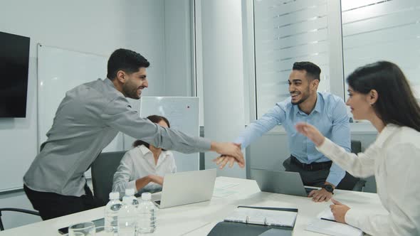 Excited Multicultural Cheerful Businesspeople Sitting Together at Meeting Giving High Five Gesture