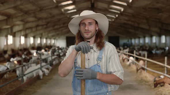 Positive Caucasian Farmer Holding Shovel at Ranch with Goats
