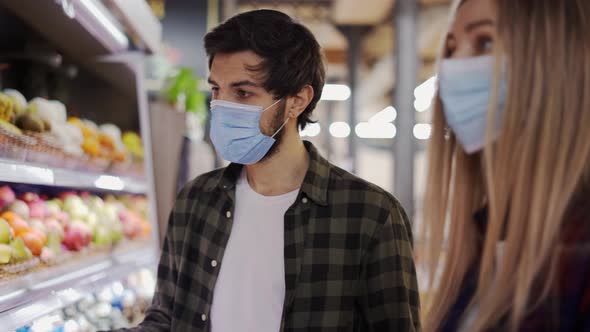 Young Couple in Face Masks Shopping for Fresh Produce at Market