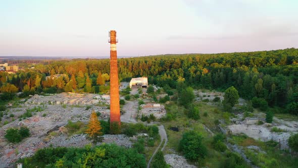 Old brick pipe among nature. Tall factory tower on abandoned place in the countryside