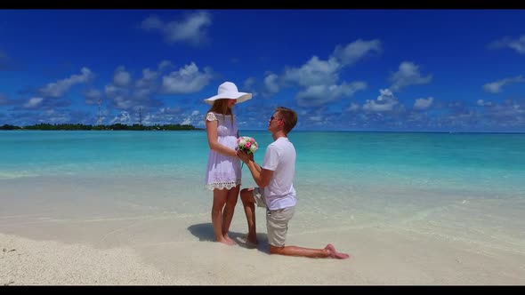 Two people happy together on paradise island beach trip by shallow sea with bright sandy background 