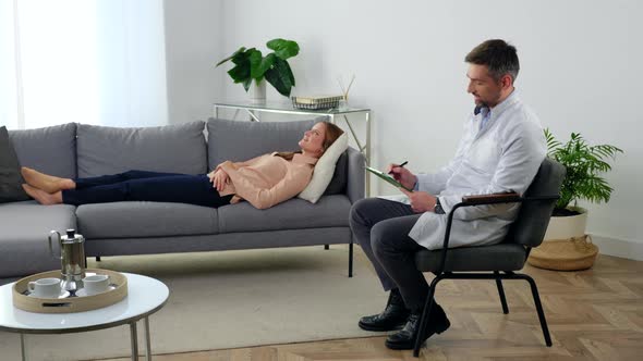 Smiling Man Doctor Psychotherapist with Clipboard Talking Patient in Clinic