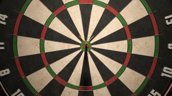 Darts arrow hitting in the bullseye of the dartboard hanging on the dark wall.