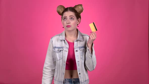 Girl with a Gold Card Upset She Does Not Have Money. Pink Background. Slow Motion