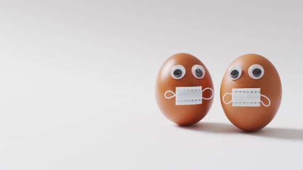 Video of eggs with eyes and face masks on a white surface