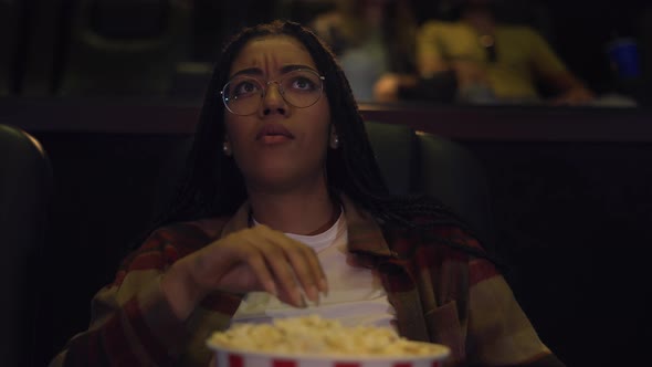 Diverse Raced Woman Sitting in Armchair Watching a Movie at the Cinema Eating Popcorn