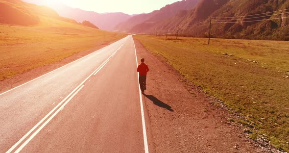 Low Altitude Flight in Front of Sporty Man at Perfect Asphalt Road