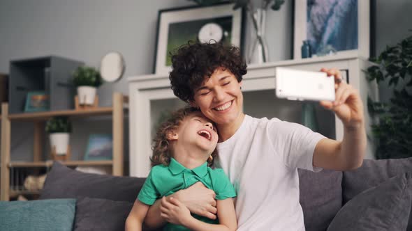 Adorable Child and Young Lady Mom Taking Selfie with Smartphone Camera Laughing