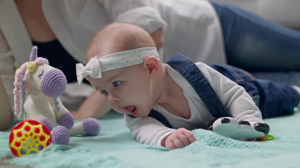 Little Girl Kid Plays a Rattle on the Floor with Parents