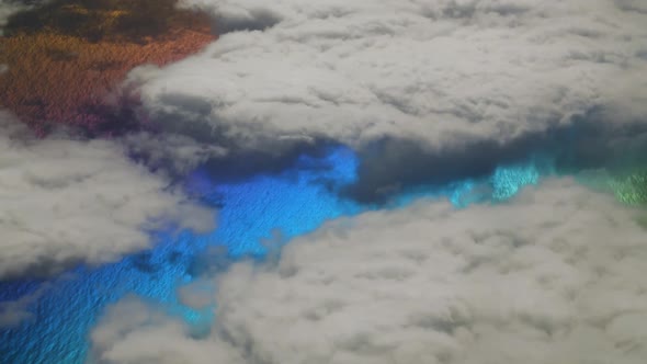Strange planet with multicolor sea water between white clouds seen from above