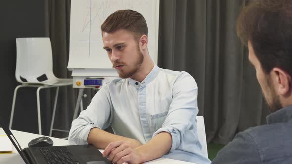 Young Businessman Showing His Mature Colleague Something on the Laptop