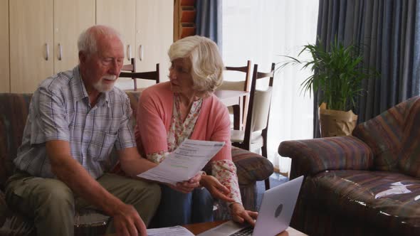 Senior couple in social distancing using laptop