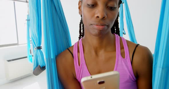 Woman talking on mobile phone while sitting on hammock swing 4k