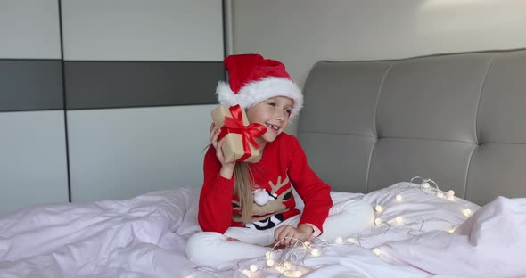 Happy Adorable Caucasian Little Girl with Blonde Hair Eight Years Old Wearing Red Santa Hat and