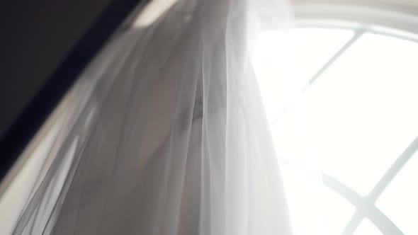 Side angle shot of a beautiful wedding dress hanging from a large church window sill - Slow motion l