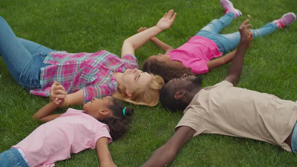United Family Holding Hands Lying on Lawn in Circle