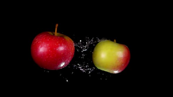 Two Ripe Apples are Flying Towards Each Other Colliding on the Black Background