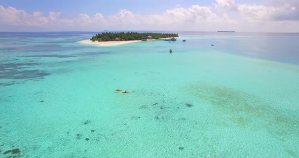 Aerial drone view of a man and woman couple kayaking around a tropical island.