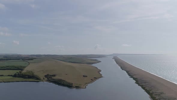 Aerial tracking forward looking east along the fleet lagoon and chesil beach at Abbotsbury. On the h