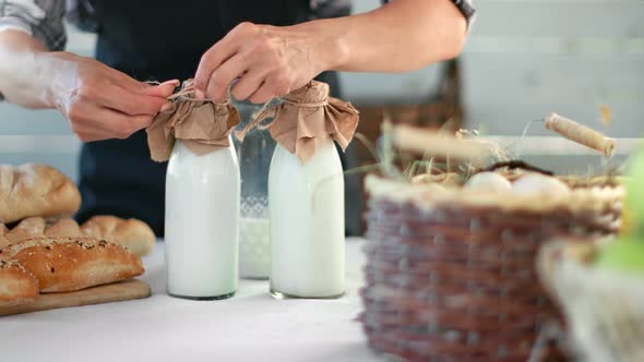 Female Farmer Hands Packaging Bottles of Homemade Milk Tie Rope