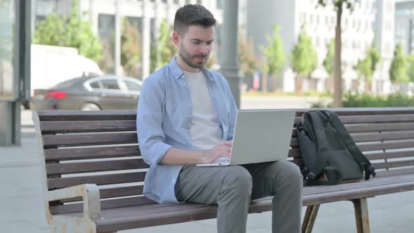 Coughing Young Man Using Laptop While Sitting on Bench